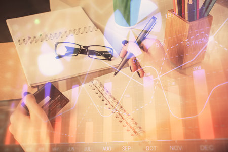 Multi exposure of woman on-line shopping holding a credit card and financial graph drawing. Stock market E-commerce concept.の写真素材
