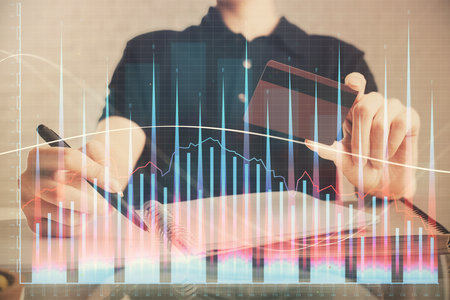 Double exposure of man hands holding a credit card and Forex graph drawing. Stock trading and digital fintech in Internet E-commerce concept.の写真素材