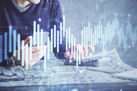 Double exposure of man's hands holding and using a digital device and forex graph drawing. Financial market concept.の写真素材