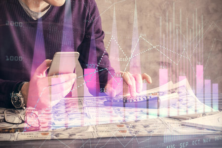 Double exposure of man's hands holding and using a digital device and forex graph drawing. Financial market concept.の写真素材