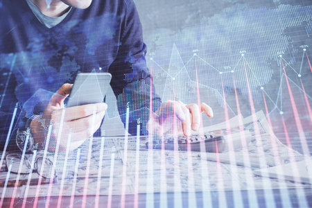 Double exposure of man's hands holding and using a digital device and forex graph drawing. Financial market concept.の写真素材