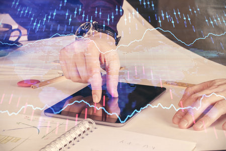 Double exposure of man's hands holding and using a digital device and forex graph drawing. Financial market concept.の写真素材