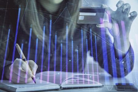 Double exposure of woman on-line shopping holding a credit card and financial graph drawing. Stock market E-commerce concept.の写真素材