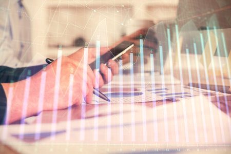 Double exposure of man's hands holding and using a phone and financial chart drawing. Market analysis concept.の写真素材