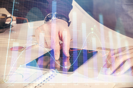 Double exposure of man's hands holding and using a digital device and forex graph drawing. Financial market concept.の写真素材