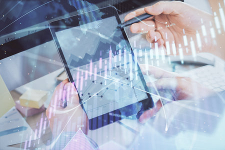 Double exposure of man's hands holding and using a phone and financial chart drawing. Market analysis concept.の写真素材