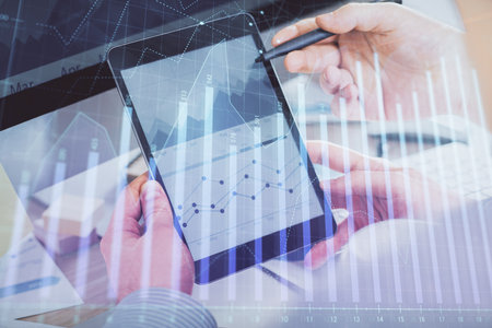 Double exposure of man's hands holding and using a phone and financial chart drawing. Market analysis concept.の写真素材