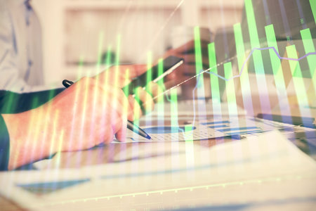 Double exposure of man's hands holding and using a phone and financial chart drawing. Market analysis concept.の写真素材