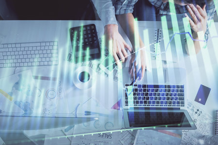 Double exposure of man and woman working together and financial graph hologram drawing. market analysis concept. Computer background. Top View.の写真素材