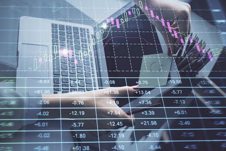 Double exposure of businesswoman hands typing on computer and financial graph hologram drawing. Stock market analysis concept.の写真素材