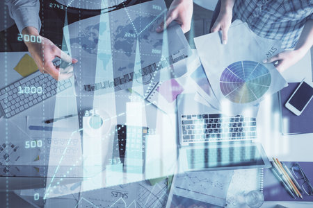 Double exposure of man and woman working together and financial chart hologram drawing. market analysis concept. Computer background. Top View.の写真素材