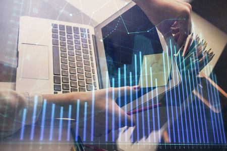Double exposure of businesswoman hands typing on computer and financial graph hologram drawing. Stock market analysis concept.の写真素材