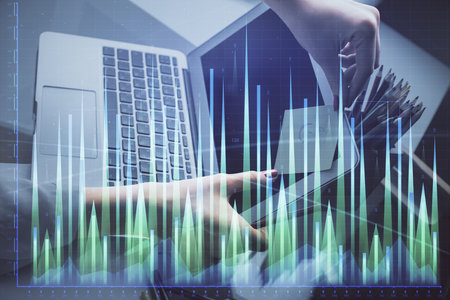 Double exposure of businesswoman hands typing on computer and financial graph hologram drawing. Stock market analysis concept.の写真素材