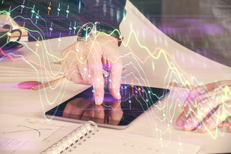 Double exposure of man's hands holding and using a digital device and forex graph drawing. Financial market concept.の写真素材