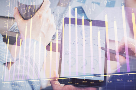 Double exposure of man's hands holding and using a phone and financial chart drawing. Market analysis concept.の写真素材