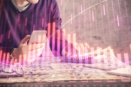 Double exposure of man's hands holding and using a digital device and forex graph drawing. Financial market concept.の写真素材