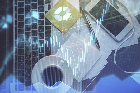 Double exposure of financial chart drawing over table background with computer. Concept of research and analysis. Top view.の写真素材