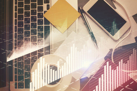 Double exposure of financial chart drawing over table background with computer. Concept of research and analysis. Top view.の写真素材