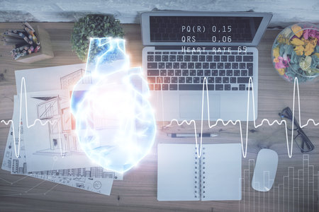 Heart hologram drawings over computer on the desktop background. Top view. Multi exposure. Concept of medical education.の写真素材
