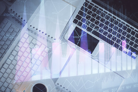 Financial market graph and top view computer on the desktop background. Multi exposure. Investment concept.の写真素材
