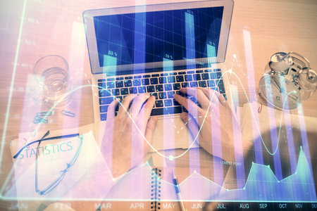 Double exposure of man's hands typing over laptop keyboard and forex chart hologram drawing. Top view. Financial markets concept.の写真素材