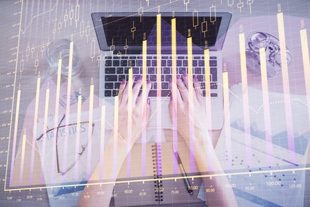 Double exposure of woman hands working on computer and forex graph hologram drawing. Top View. Financial analysis concept.の写真素材