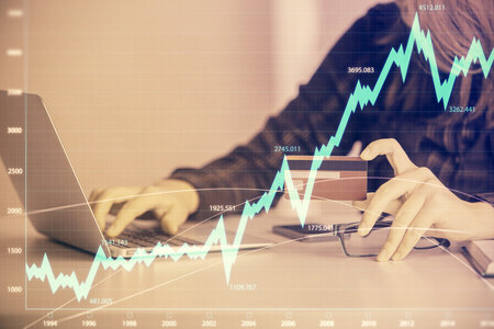 Double exposure of woman on-line shopping holding a credit card and financial graph drawing. Stock market E-commerce concept.の写真素材