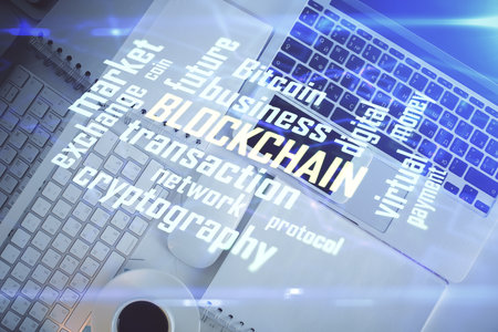 Blockchain theme hologram drawings over computer on the desktop background. Top view. Double...