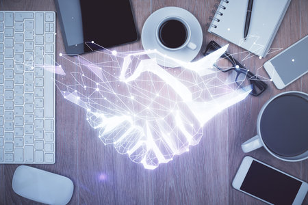 Multi exposure of handshake drawing over table with phone. Top view. Concept of partnership.の写真素材