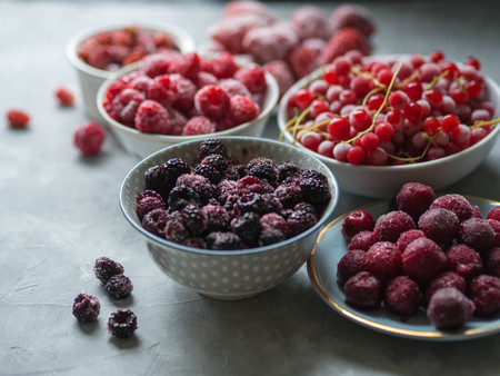 several bowls of frozen berries on a gray table. Wild strawberries, cherries, black raspberries, raspberries and red currantsの写真素材