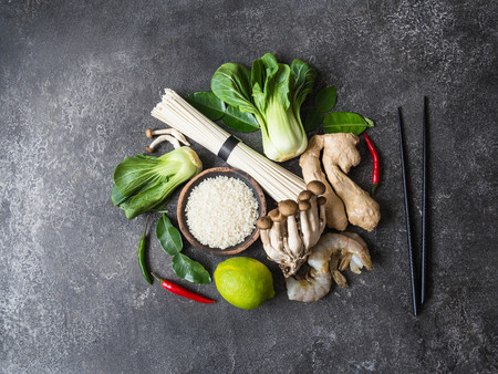 Various Asian ingredients in the form of a circle and black chopsticks on gray background. Copy space. Top viewの写真素材