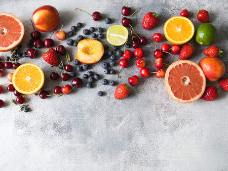 Various berries and fruits on a gray background. Strawberries, cherries, orange, peach, blueberries, lime, grapefruit. Top view Copy spaceの写真素材