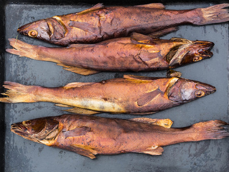 Four pike fish perch smoked on black tray. Top viewの写真素材