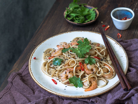Fresh noodles with prawns, chili, soy sauce, cilantro and black sesame. Asian noodles with prawns, chili and parsley on a white plate with chopsticksの写真素材