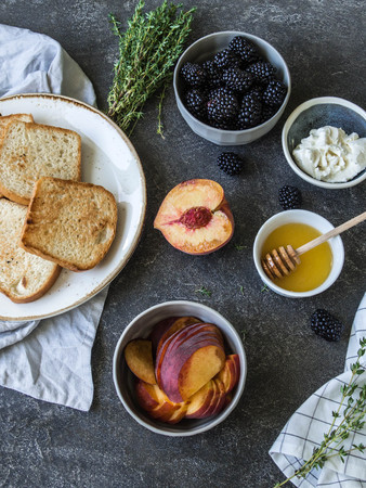 Ingredients for making delicious toasts with cream cheese, peach or blackberries, thyme and honey.の写真素材