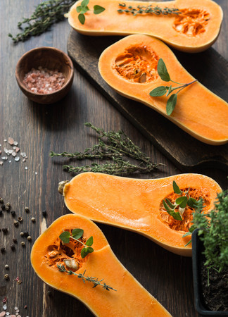 Fresh orange muscat pumpkin, cut in half, ready for baking with spices and herbsの写真素材