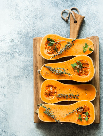 Fresh orange muscat pumpkin, cut in half, ready for baking with spices and herbsの写真素材