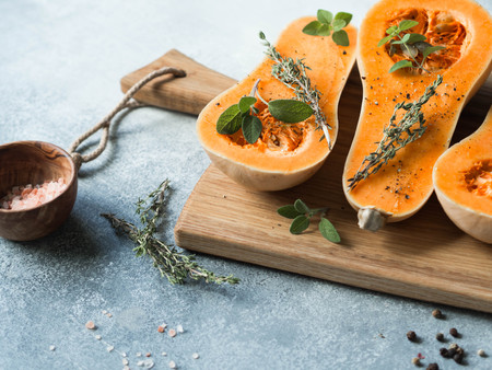 Fresh orange muscat pumpkin, cut in half, ready for baking with spices and herbsの写真素材