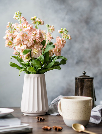 A bouquet of pink mattiol flowers in a vase, a vintage coffee pot, cup with coffee and spices on a wooden brown table. Lifestyleの写真素材