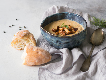 Chanterelle cream soup in blue bowl and baguette on the linen napkin. Autumn food concept. Top viewの写真素材