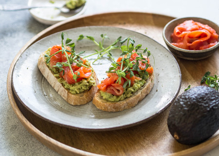 Toasts with avocado and salted salmon with fresh pea sprouts on a plateの写真素材
