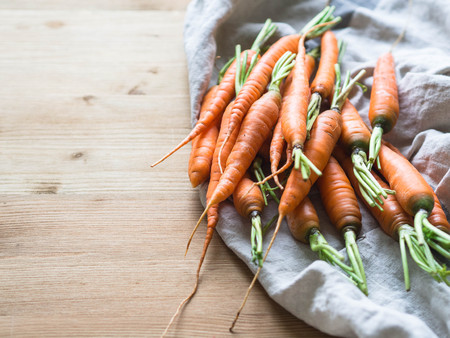 fresh young orange carrots on a kitchen towel on a wooden table.の写真素材