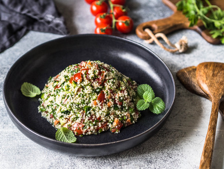 Oriental tabbouleh salad with couscous, vegetables and herbs in a black bowlの写真素材