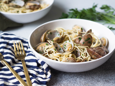 Spaghetti with clams, garlic and parsley in a white bowls, napkins and gold appliancesの写真素材
