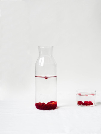 Water with red berries viburnum in a glass jug on a whiteの写真素材