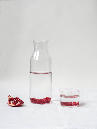 Water with pomegranate seeds in a glass jug on a whiteの写真素材