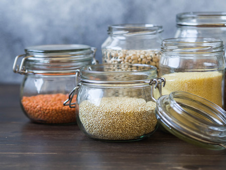 Open glasses jars with pasta, lentils, couscous, beans and quinoa on table.の写真素材