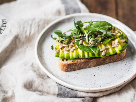 Green healthy sandwich made from spinach, sprouts, avocado and various seeds on a white plateの写真素材