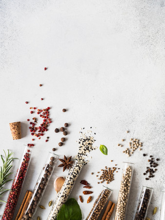 Various spices in glass test tubes and fresh herbs on grayの写真素材