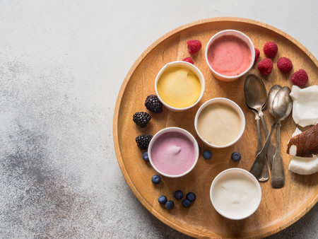 Fresh fruit ice cream of different colors in paper cups on a gray